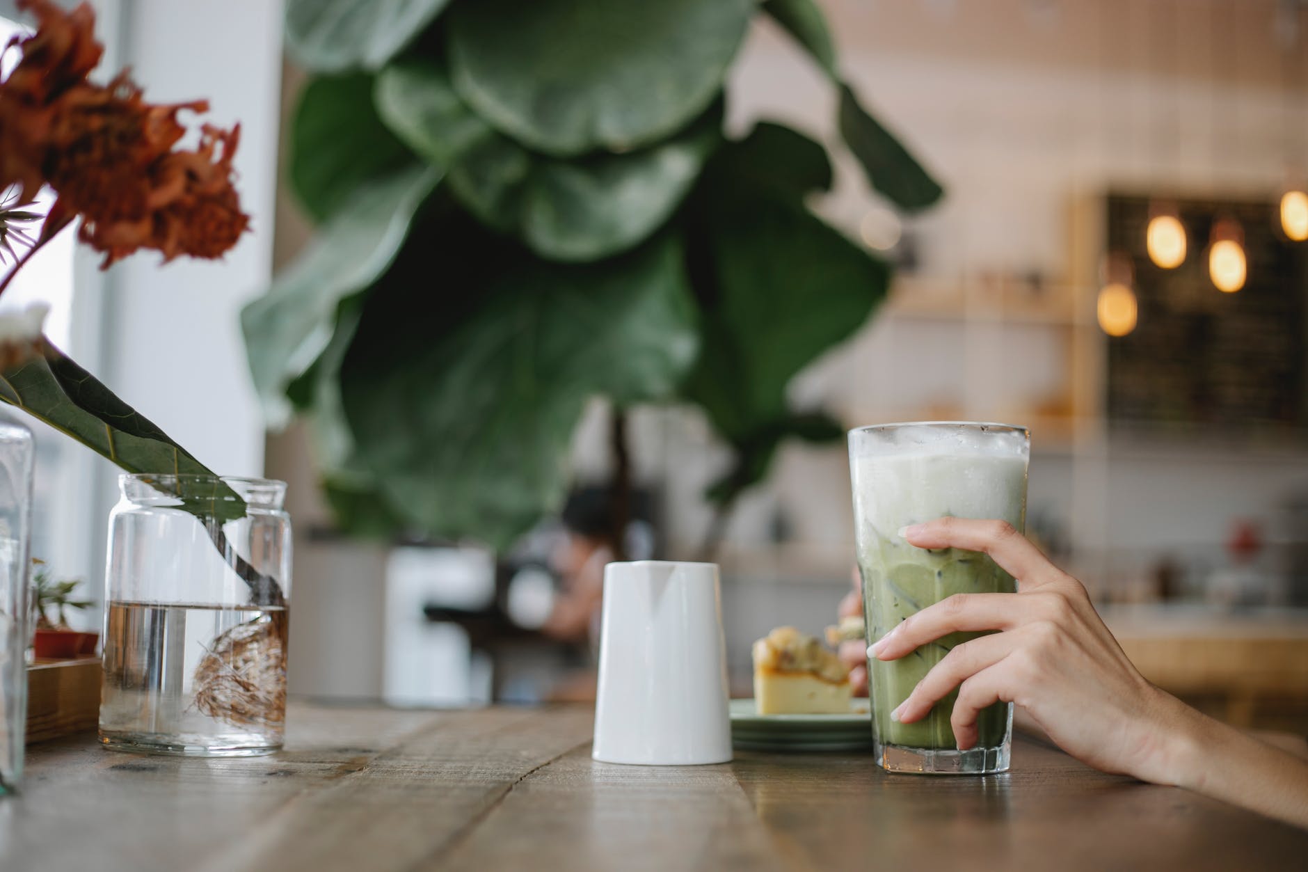 crop unrecognizable woman drinking refreshing matcha latte in cafe